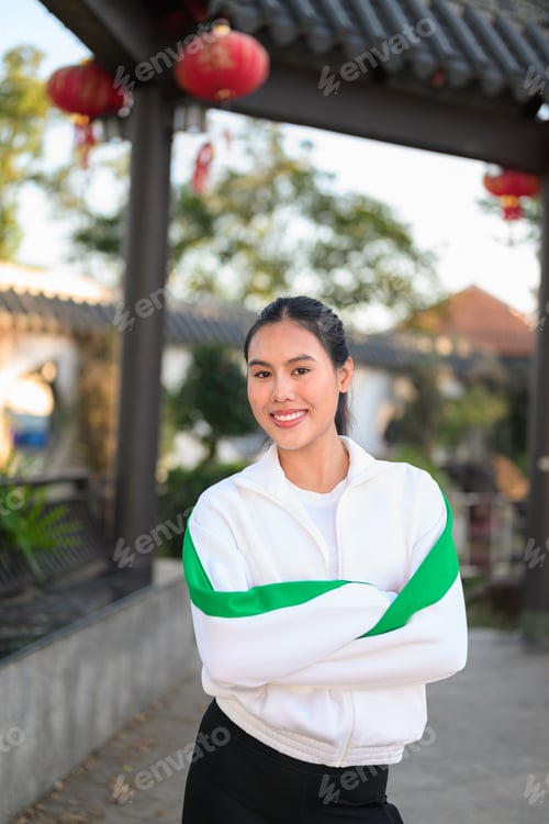 Preview: Young Asian Woman in Sporty Casual Outfit Outdoors With Arms Crossed