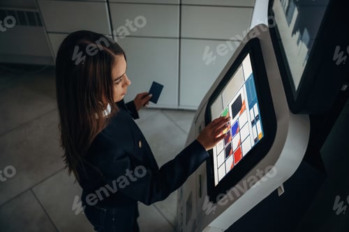 Preview: Woman is using banking terminal indoors