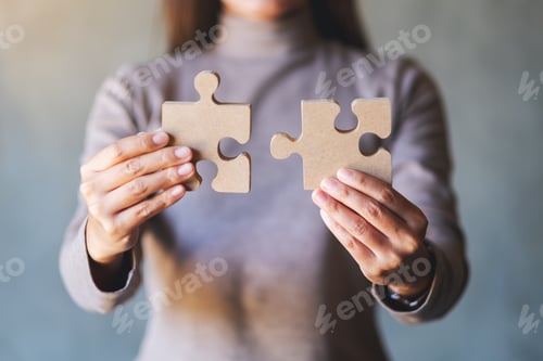 Preview: Closeup image of a woman holding and putting a piece of wooden jigsaw puzzle together