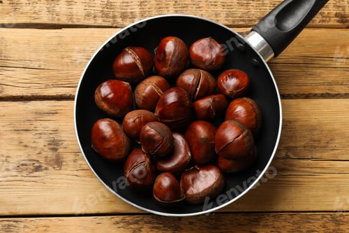 Preview: Fresh edible sweet chestnuts in frying pan on wooden table, top view