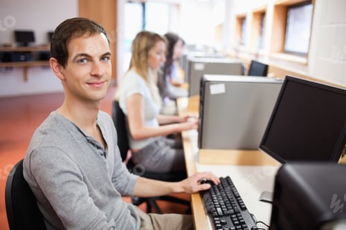 Preview: Smiling Male Student Posing With A Computer In An It Room
