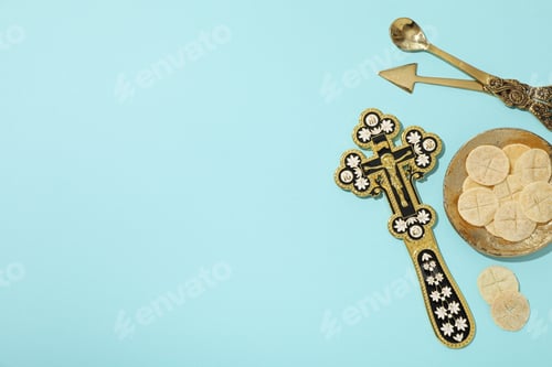 Preview: Golden cross and liturgical bread on golden plate on blue background, space for text