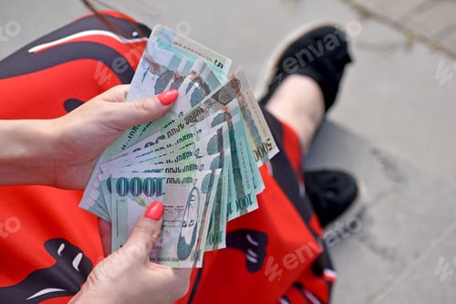 Preview: Top view of female hands in red dress holding and counting many Armenian thousand dram bills