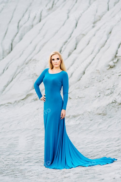 Preview: blonde girl in a blue dress with blue eyes in a granite quarry