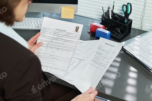 Preview: Middle Aged Woman Reviewing Visa Application Documents at Desk