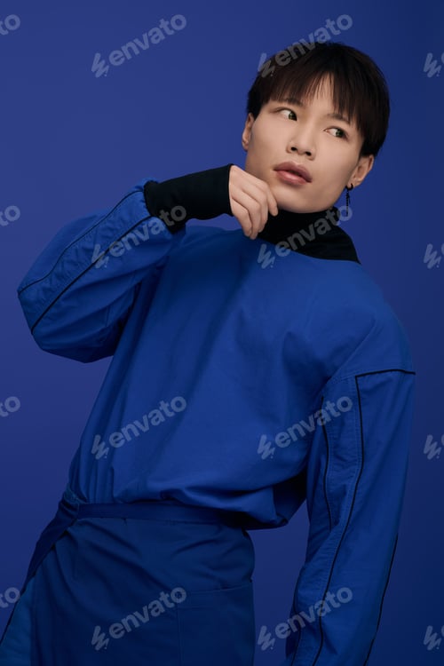Preview: Charming young asian man poses confidently in striking blue attire against a solid background