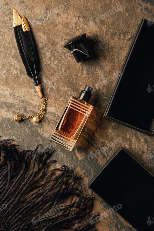 Preview: top view of perfume and decorative black feathers on brown weathered surface