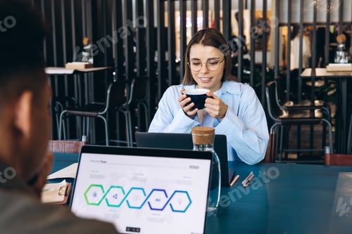 Preview: Businesswoman drinking coffee while working on laptop in cafe