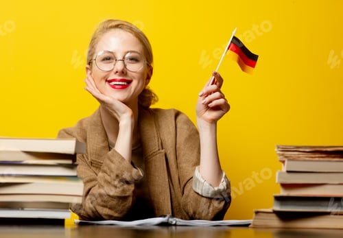 Preview: Style blonde woman sitting at table with books and flag of Germany on yellow background