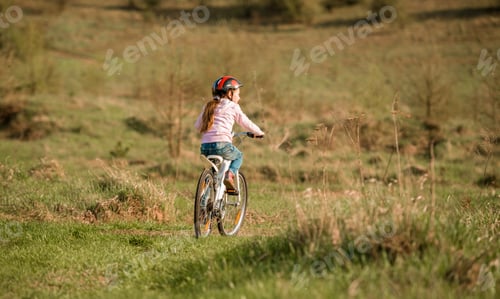 Preview: smiling little girl riding a bike turned away