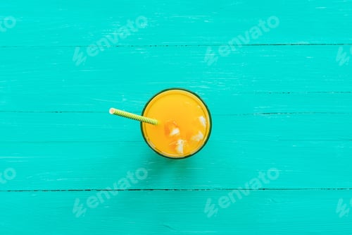 Preview: Orange juice in a glass on turquoise blue wooden table, top view