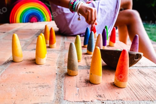 Preview: Girl out of focus in the background, playing with some pieces of colored wood