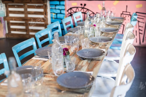 Preview: Long rustic dinner timber table with vintage retro chairs set with plates and glasses for a large