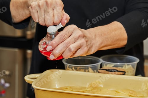 Preview: Step by step potato gratin recipe. Hands pepper slices of potatoes in glass baking dish. Potato