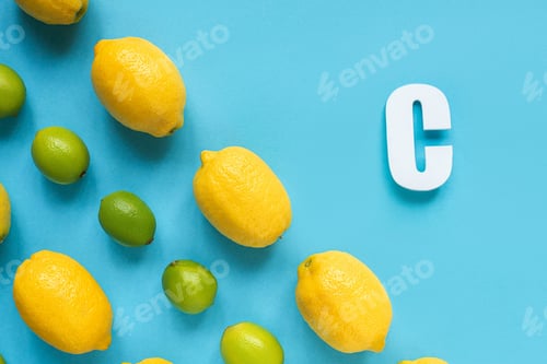 Preview: flat lay with ripe yellow lemons, green limes and letter C on blue background