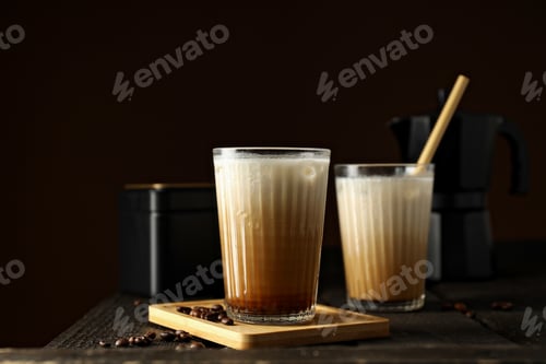 Preview: Glasses with iced coffee, coffee maker and coffee beans on dark brown background, close up