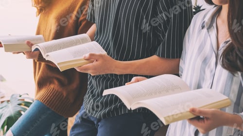 Preview: Group of young people sitting and enjoyed reading books together on wooden table
