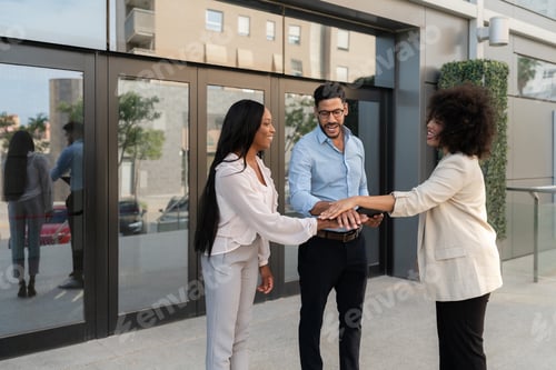 Preview: Multiracial business people joining hands in front of office building