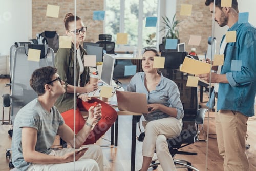 Preview: Four Coworkers Communicating Together In Meeting Room. Stickers Are On Glass