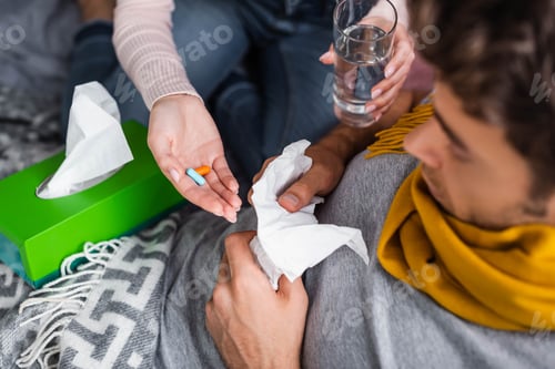 Preview: cropped view of girlfriend taking pills and glass of water to sick boyfriend
