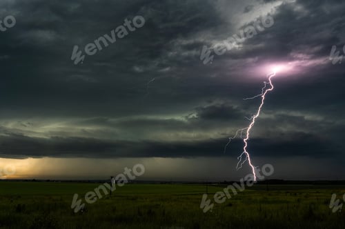 Preview: Beautiful shot of lightning strike in the night sky over a grassy field on a stormy night