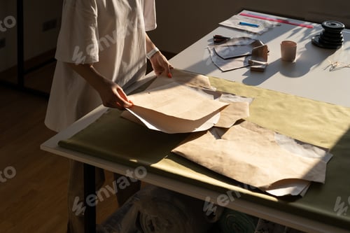 Preview: Unrecognizable designer hold new sewing patterns on paper. Female tailor work with clothes models