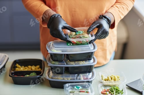 Preview: Close up of woman holding stack of plastic containers packing food delivery order, copy space