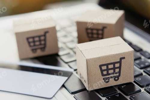 Preview: Shopping online. Credit card and cardboard box with a shopping cart logo on laptop keyboard.