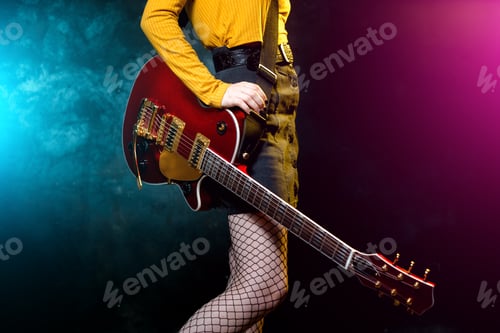 Preview: Close-up photo of young hipster woman legs and red guitar in neon lights. 90s style concept.