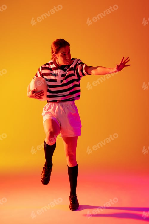 Preview: Caucasian female rugby player with rugby ball over neon pink lighting