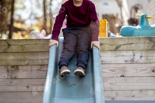 Preview: Selective focus shot of a boy sliding down a slide