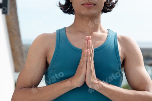 Preview: Biracial man doing yoga, meditating on balcony
