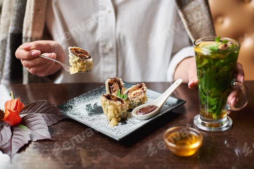 Preview: Girl in white holding drink eating sweet sushi roll.