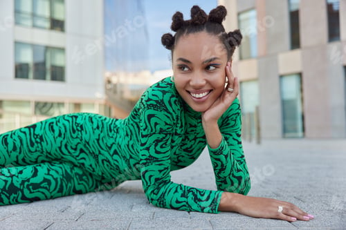 Preview: Horizontal shot of positive teenage girl with combed hair buns bright makeup smiles toothily looks a