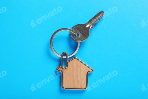 Preview: Key with trinket in shape of house on blue background, top view. Real estate agent services