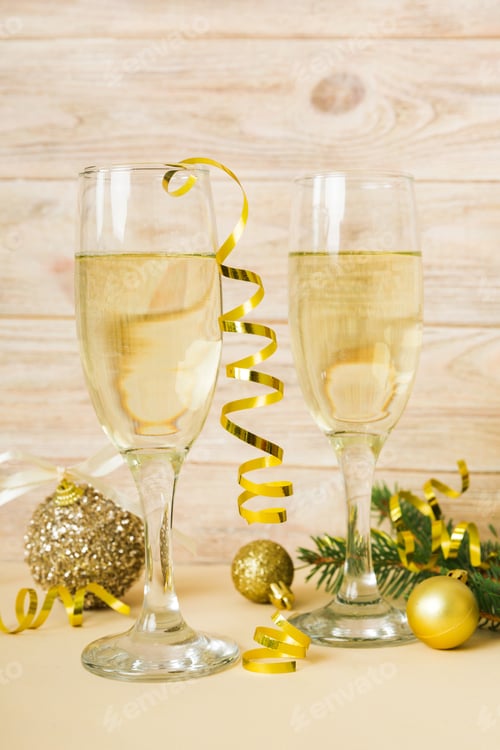 Preview: Champagne glasses and christmas decor on colored holiday background. Flat lay New Year decorations
