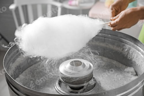 Preview: Woman making cotton candy using modern machine indoors, closeup