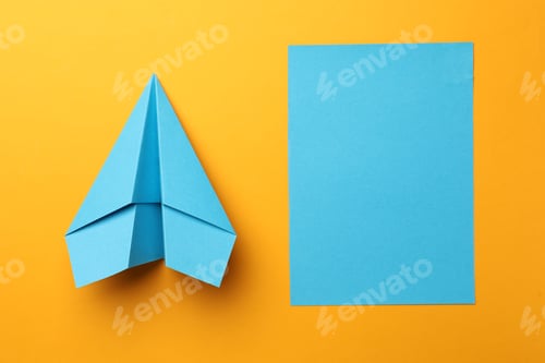 Preview: Handmade light blue plane and piece of paper on yellow background, flat lay