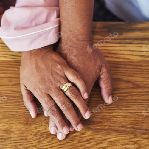 Preview: High angle closeup of an unrecognizable couple holding hands on a table at home during the day