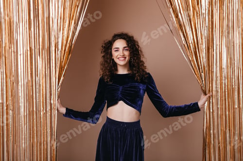 Preview: Smiling lady in dark blue outfit posing on background of gold curtains