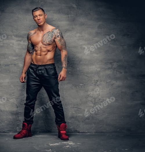 Preview: Shirtless muscular male fitness model with tattoo on his chest.