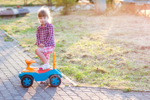 Preview: Little cute girl outdoors with a toy car on a sunny day