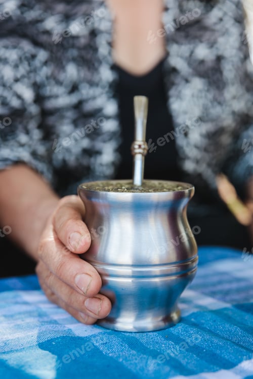 Preview: a senior female holding a metal cup with a drink