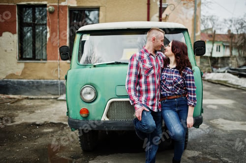 Preview: Stylish couple wear on checkered shirt in love together against old minivan.