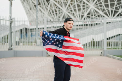 Preview: a young man in black clothes waving usa american flag outdoors