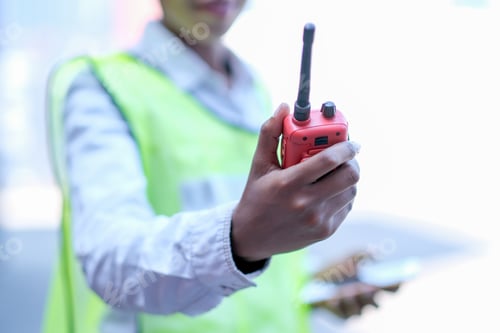 Preview: Hand of technician worker woman hold and shows red walky-talky in cargo container area