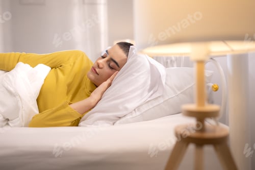 Preview: A woman sleeping peacefully on a soft white bed, resting comfortably in a bright and serene bedroom