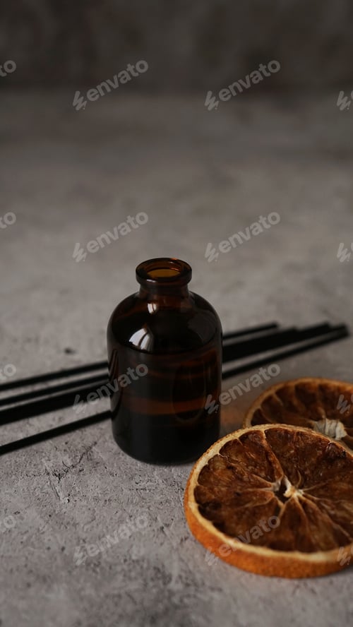 Preview: Citrus reed diffuser on dark background. Bottle, sticks and dry oranges
