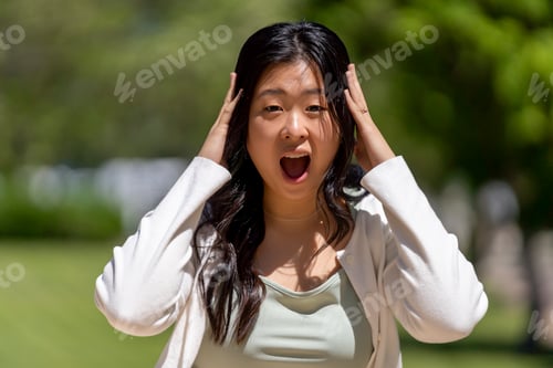 Preview: Outraged teenager throws his hands on his head celebrating success in a park