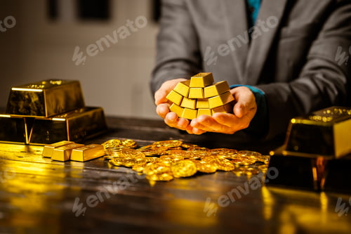Preview: A businessman sits at his desk in a nighttime office, using a laptop to analyze gold bar prices